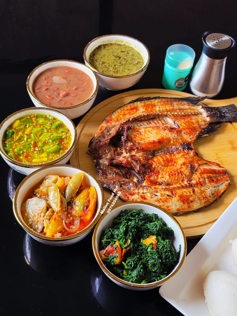 Whole grilled fish on wood board with sides