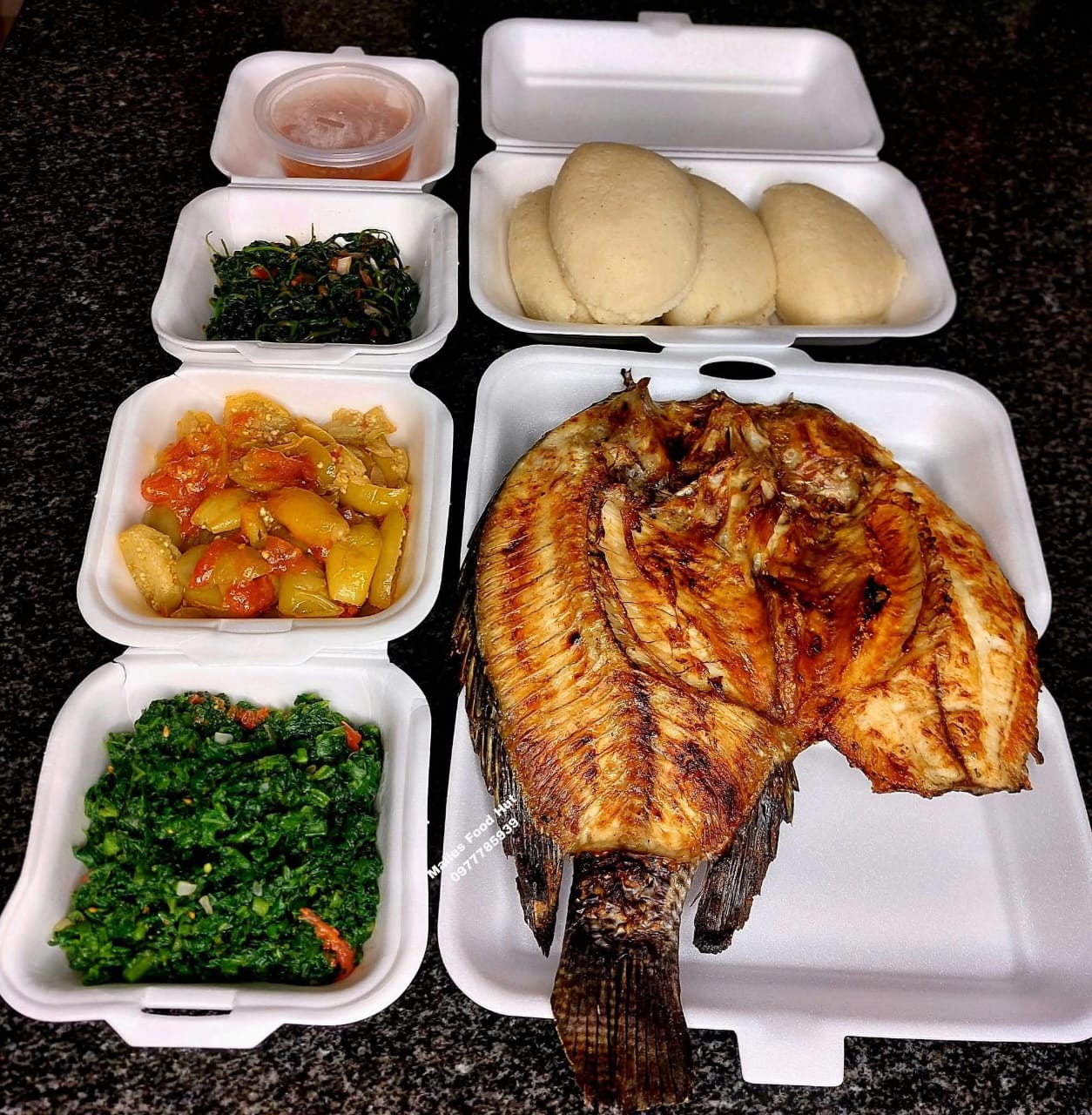 Whole fried fish with nsima and six relish bowls